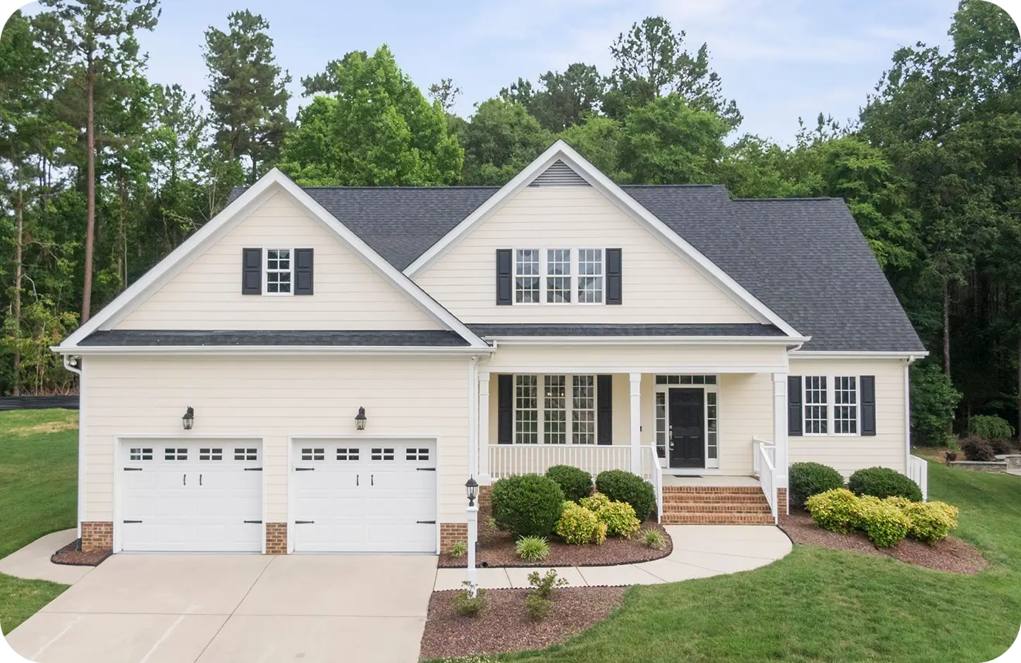 Beautiful two-story suburban house with cream siding, dark shutters, and an attached double garage