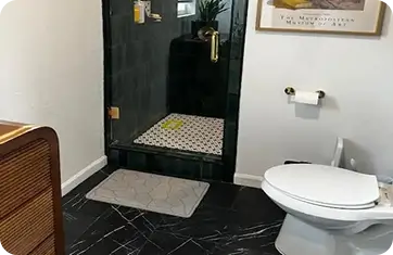 Contemporary bathroom renovation featuring sleek black marble floor tiles and a dark glass shower