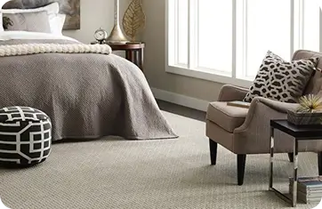 Cozy bedroom corner showcasing neutral textured carpeting, a plush armchair, and patterned accent pillows