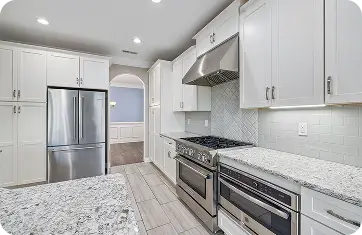 Modern kitchen featuring white cabinets, granite countertops, and stainless steel appliances with tile flooring