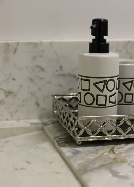 This white and black geometric ceramic soap dispenser from the Sovereign bath set rests on an open-work silver-tone metal tray