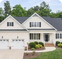 Two-story cream-colored family home with a dark shingle roof and immaculate front yard landscaping